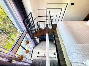 a room with a balcony with a bed and a staircase at Utopia Loft Condo Naiharn Beach in Nai Harn Beach +26 photos