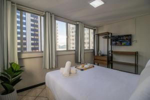 1 dormitorio con 1 cama blanca grande y ventanas grandes en CLR81 - Calçadão, 1 Dorm Climatizado, Garagem, en Balneário Camboriú