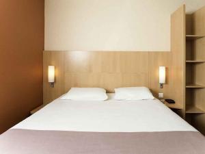 a bedroom with a large white bed with two pillows at ibis Issy les Moulineaux "Val de Seine" in Issy-les-Moulineaux +101 photos
