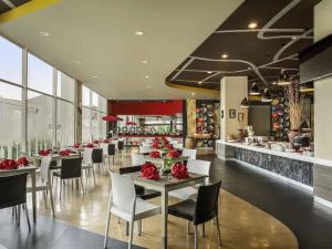 a restaurant with tables and chairs with red roses on them at Ibis Surabaya City Center in Surabaya