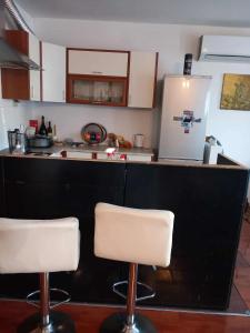 a kitchen with two white stools in front of a counter at Stan na dan Vila Dizdar in Goražde