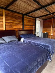zwei Betten in einem Zimmer mit Holzwänden in der Unterkunft Costa Azul Refugio Frailejon in Tibasosa