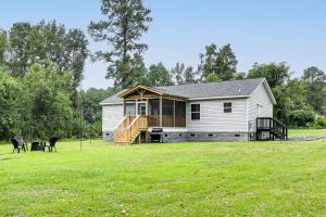 a white house with a deck and a dog in a field at Dog Friendly, Screened Porch St Stephen Retreat! in Saint Stephen