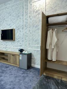 a room with a bed and a tv on a wall at Turkistan in Türkistan