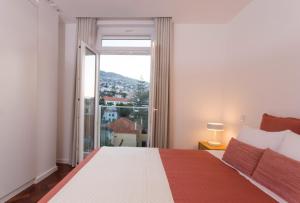 a bedroom with a bed and a large window at BJ Apartments Funchal in Funchal