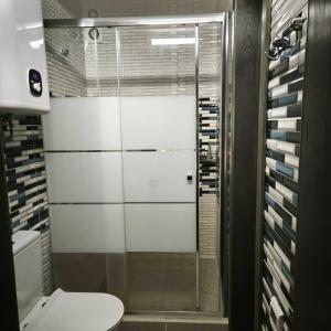 a bathroom with a toilet and a glass shower at Будинок з басейном і сауною in Podgortsy