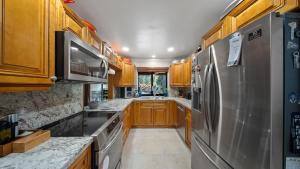 a kitchen with wooden cabinets and a stainless steel refrigerator at Luxury Queen Room, Walk to UM, Free Car Service! in Miami
