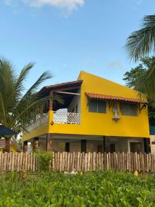 a yellow house with a fence in front of it at Casa a beira Mar - Ponta de Mangue - Maragogi in Maragogi