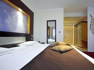 a large bed with two pillows on it in a bedroom at Mercure Olbia in Olbia +217 photos