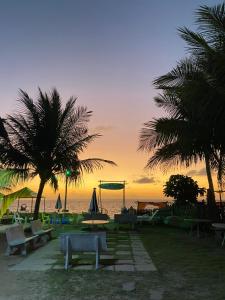 a beach with palm trees and a playground at sunset at Pousada Veruschka Santiago in Maragogi