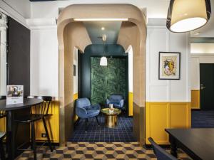 a restaurant with blue chairs and a yellow wall at ibis Styles Paris Cadet Lafayette in Paris