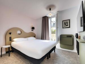 a bedroom with a large white bed and a window at ibis Styles Paris Cadet Lafayette in Paris