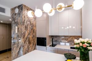 a kitchen with white cabinets and a vase of flowers at Vidok 201 in Olsztyn
