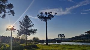 a rainbow in the sky over a lake with trees at Pousada refúgio do lago in Lages +3 photos