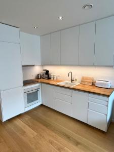 a kitchen with white cabinets and a sink at New apartment in Hoyvík in Hoyvík +1 photo