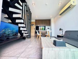 a living room with a couch and a staircase at Utopia Loft Condo Naiharn Beach in Nai Harn Beach