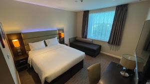 ドーハにあるPremier Inn Doha Education Cityのベッドと椅子のあるホテルの部屋