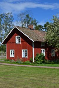 eine rote Scheune mit weißen Fenstern auf einem Feld in der Unterkunft Uddebogård 2 in Hjo