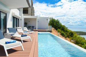a villa with a swimming pool and chairs on a deck at New Condo Eternal Sea - 3 Bedrooms in Koolbaai