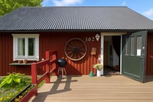 una casa rossa con una ruota sul lato di Charming Swedish Summer Cottage - Happy Rentals a Motala