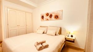 Un dormitorio con una cama blanca con una toalla encima. en central in Los Cristianos Balcony and beach on foot, en Los Cristianos