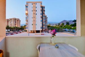 Un jarrón de flores sobre una mesa con vistas a un edificio. en central in Los Cristianos Balcony and beach on foot, en Los Cristianos