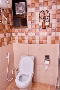 a bathroom with a toilet and a window with a fan at 3 - bedroom duplex apartment in upanga in Dar es Salaam +7 photos