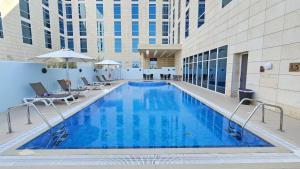 a large pool in a hotel with chairs and a building at Premier Inn Doha Education City in Doha +58 photos