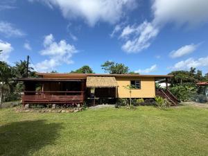 a small yellow house with a large yard at Hava'i Lodge in Taputapuapea