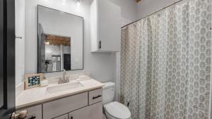 a bathroom with a toilet and a sink and a mirror at Charming & Spacious Hideaway by Downtown Bryan in Bryan +6 photos