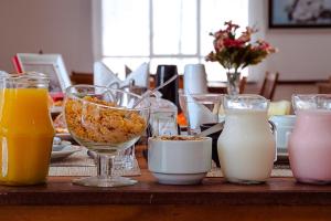 a table topped with glasses of milk and other drinks at VELINN Pousada Vila Floratta in Campos do Jordão