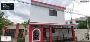 梅里达Cuarto GG EZ 2的一座红色和白色的建筑,设有加油站