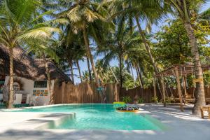 a swimming pool with palm trees and a fence at Mintaka Boutique Hotel in Bwejuu