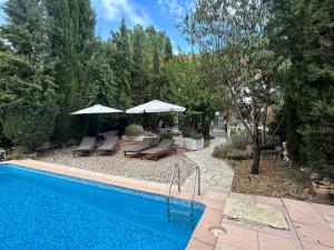 a swimming pool with patio furniture and umbrellas at Casa La Nuez in Almedinilla