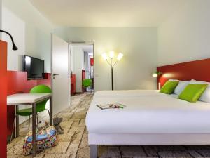 a hotel room with a bed and a desk at ibis Styles Karlsruhe Ettlingen in Ettlingen +79 photos