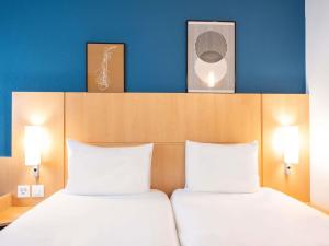a bedroom with two beds and two pictures on the wall at ibis Genève Centre Nations in Geneva +42 photos