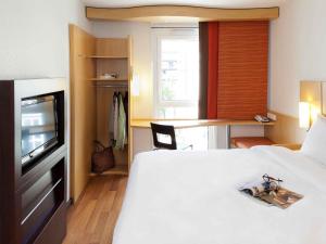 a hotel room with a bed and a television at ibis München City Süd in Munich