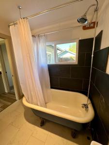 Un baño con bañera y cortina de ducha. en Ashland Bungalow downtown, en Ashland