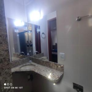 a bathroom with a sink and a large mirror at Apartamento inteiro in Itaperuna