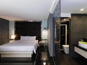 a bedroom with a bed and a bathroom with a tub at ibis Styles Chiang Mai in Chiang Mai