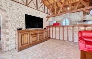 a living room with a television and a red chair at Charmante Maison Avec Piscine in Saint-Pierre-dʼEyraud
