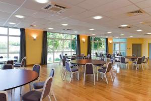 a conference room with tables and chairs and windows at ibis Styles Bourbon Lancy in Bourbon-Lancy
