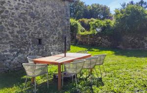 a wooden table and chairs in front of a stone wall at Pet Friendly Home In Royères With Wifi in Chénour
