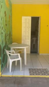 a table and a chair next to a yellow wall at Casa a beira Mar - Ponta de Mangue - Maragogi in Maragogi