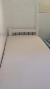 a white bed in a white room with a bench at Casa a beira Mar - Ponta de Mangue - Maragogi in Maragogi