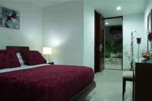 a bedroom with a bed with a purple blanket at Hotel Cariongo Pamplona in Pamplona
