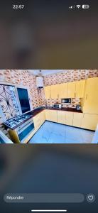 a kitchen with yellow cabinets and a brick wall at maison avec bar privé à kintélé in Brazzaville