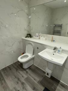 a white bathroom with a toilet and a sink at Ideal Heathrow Base 2BR 2BA Apt in Hounslow in Hounslow +25 photos