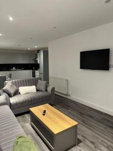 a living room with a couch and a tv on a wall at Ideal Heathrow Base 2BR 2BA Apt in Hounslow in Hounslow