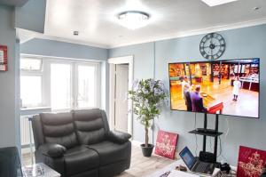 a living room with a couch and a tv on the wall at Regina's Place in London